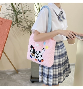 Detail of pink quilted shoulder bag featuring cute dalmation dog embroidery and blue strap