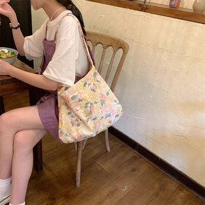 Detail of floral canvas tote bag with pink roses and yellow flowers in a vintage cafe
