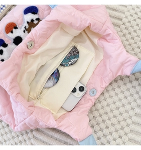 Detail of pink quilted shoulder bag featuring interior zip pocket and cute puppy embroidery