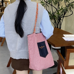 Borsa tote a quadretti rossi con tasca in denim in un accogliente ambiente da caffè