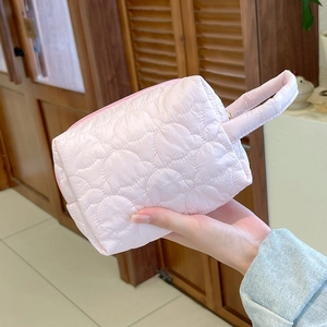 Détail d'une trousse à maquillage rose matelassée avec motif cœur et poignée solide