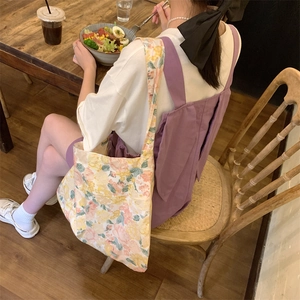 Floral canvas tote bag shown in a cozy cafe setting being worn by a model