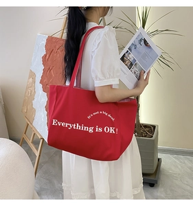 Detail der roten Canvas-Tragetasche mit 'Everything is OK!'-Slogan im Lifestyle-Hintergrund