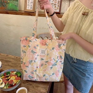 Grand sac cabas en toile à fleurs avec étiquette lapin présenté dans un décor de café