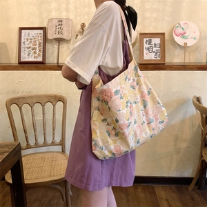 Floral canvas tote bag with pink and yellow flowers worn by model in a vintage cafe