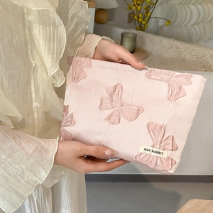Detailed close-up of pink jacquard makeup bag with embossed bow embroidery and brand tag