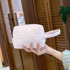 Gros plan d'une trousse à maquillage matelassée rose avec motifs de cœurs et poignée
