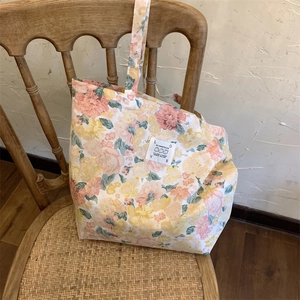 Gros plan du sac fourre-tout en toile à fleurs montrant le motif vintage et l'étiquette