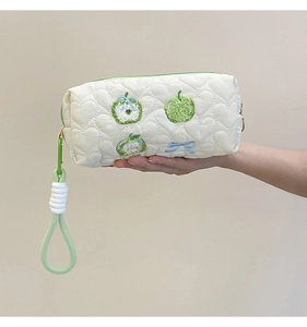 Detail of white quilted heart patterns with apple and bow embroidery on makeup bag