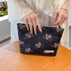 Detail of floral embroidery on black fabric makeup bag with May Rabbit label