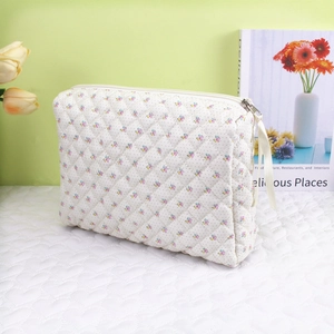 Detail view of floral quilted makeup bag with creamy fabric and pink ribbon zipper pull
