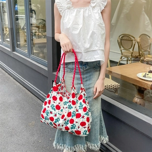 Dettaglio della grande borsa tote con stampa floreale di rose rosse e manici in corda