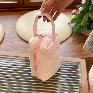 Détail d'une trousse à maquillage rose matelassée à motifs de cœurs et zip
