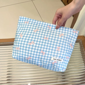 Dettaglio della trousse a quadretti blu con fiocchi rosa e logo del marchio