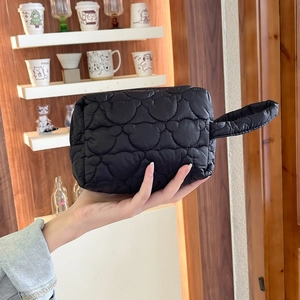 Détail de la trousse de maquillage matelassée noire avec texture nylon et poignée