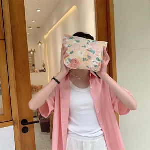 Floral makeup bag with pink flowers held by a model in a cozy indoor lifestyle setting