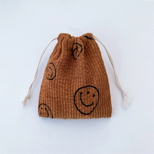 Detail of warm brown corduroy drawstring pouch showing clear texture and smiley face pattern