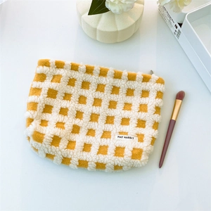Close-up of yellow and white checkered plush makeup bag with soft fleece texture