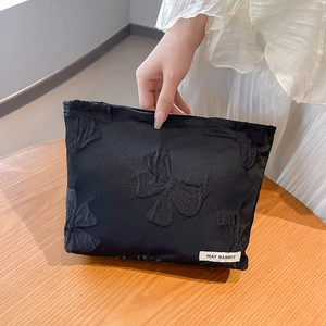 Detail of black jacquard makeup bag with butterfly embroidery and May Rabbit label