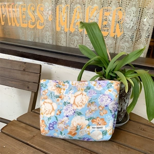 Floral makeup bag featuring colorful rose patterns on a blue canvas surface