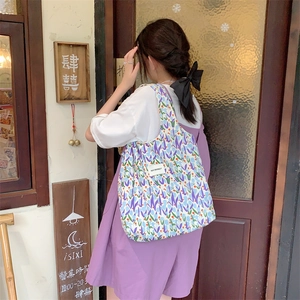 Gros plan détaillé d'un sac cabas en toile à fleurs avec tulipes et logo brodé