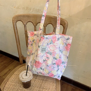 Détail d'un sac cabas en toile fleurie avec écusson lapin LOVE dans un café cosy
