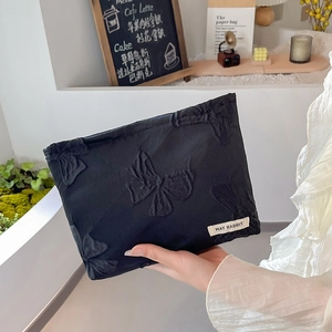 Detail of black jacquard cosmetic bag with bow pattern and May Rabbit brand label