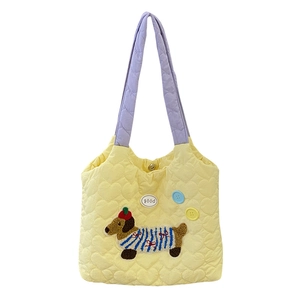 Quilted yellow shoulder bag with dog embroidery and purple handles on white background