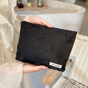 Detail of black bow-knot jacquard clutch bag featuring May Rabbit woven label design