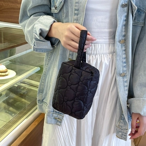 Détail d'une pochette en satin matelassé noir avec motif cœur et dragonne