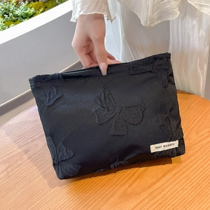 Detail of black fabric pouch with 3D butterfly embroidery and May Rabbit brand label
