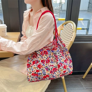 Borsa tote in tela floreale capiente con manici in corda rossa in un ambiente cafe