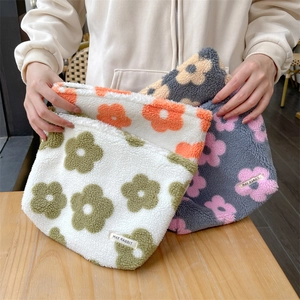 Close-up of three plush floral makeup bags with lamb wool texture and zipper closure