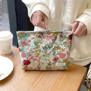 Detail of floral jacquard makeup bag with zipper closure on a wooden table