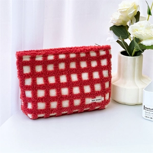 Close-up of red and white waffle plaid plush makeup bag with soft fleece texture