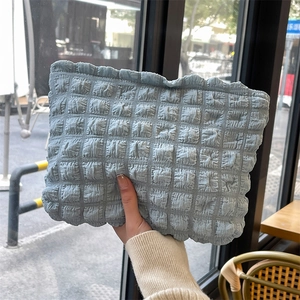 Detail of light blue bubble textured fabric on a large capacity storage clutch bag