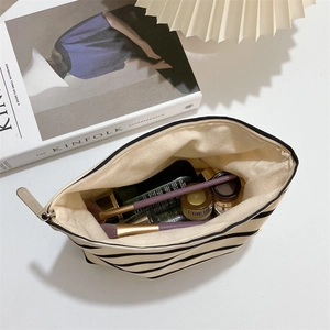 Spacious interior of striped canvas makeup bag with makeup brushes and cosmetics