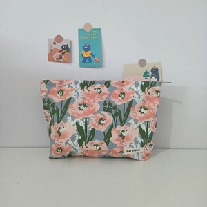 Detailed view of tulip floral pattern cosmetic bag with May Rabbit label in cozy setting