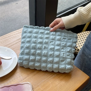 Close-up of light blue bubble fabric pouch with ruffle edges on a wooden table