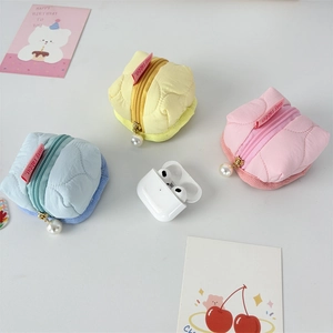 Macro view of quilted nylon mini pouches with pearl zipper detail for earbud storage
