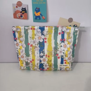 Detailed macro of floral stripe toiletry bag with metal zipper and brand label