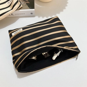 Close-up of black and gold striped canvas makeup bag showing spacious interior storage