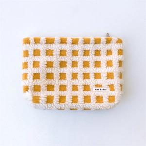 Detail of the soft yellow waffle texture and May Rabbit woven label on the cosmetic bag