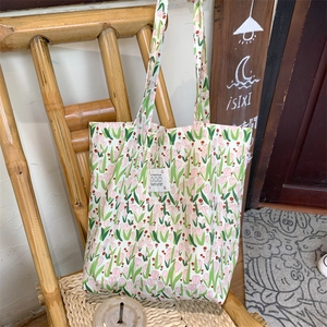 Détail d'un cabas en toile à fleurs avec motif tulipe et étiquette sur une chaise en bambou