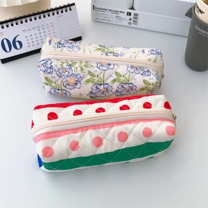 Close-up of quilted floral pencil case and polka dot organizer on a white desk