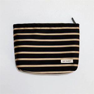 Close-up of May Rabbit striped cosmetic bag with zipper and woven label detail
