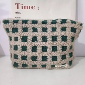 Detail of green and beige checkered waffle makeup bag with soft fleece texture and zipper