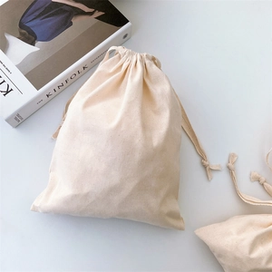 Close-up of beige cotton canvas drawstring storage bag on a minimalist white surface