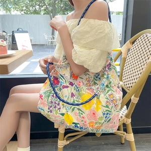 Dettaglio della borsa shopper floreale con manici in corda blu e motivi di fiori