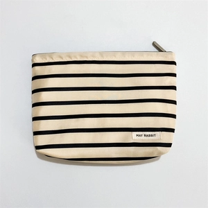 Close-up of a striped woven satin makeup bag with a durable zipper and brand label